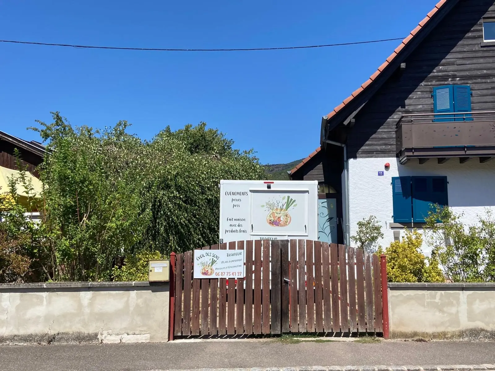 L'entrée de l'atelier au 11 rue du Moulin : portail en bois et enseigne Traiteur Éveil des Sens