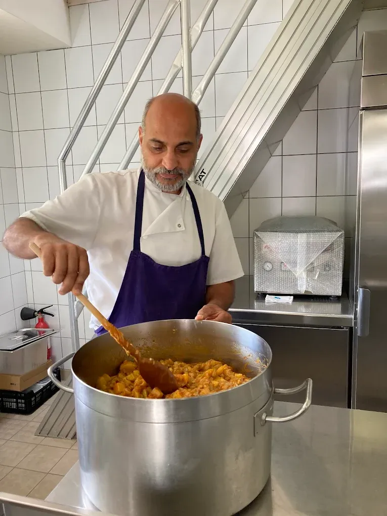 Le cuisinier remue une grande marmite de curry aux légumes à la cuillère de bois, dans l'atelier de Wihr-au-Val