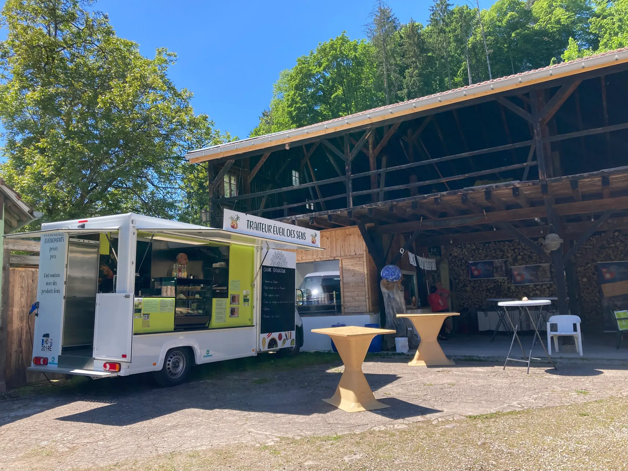 Le food truck et ses tables hautes installés dans la cour d'une ferme pour un événement