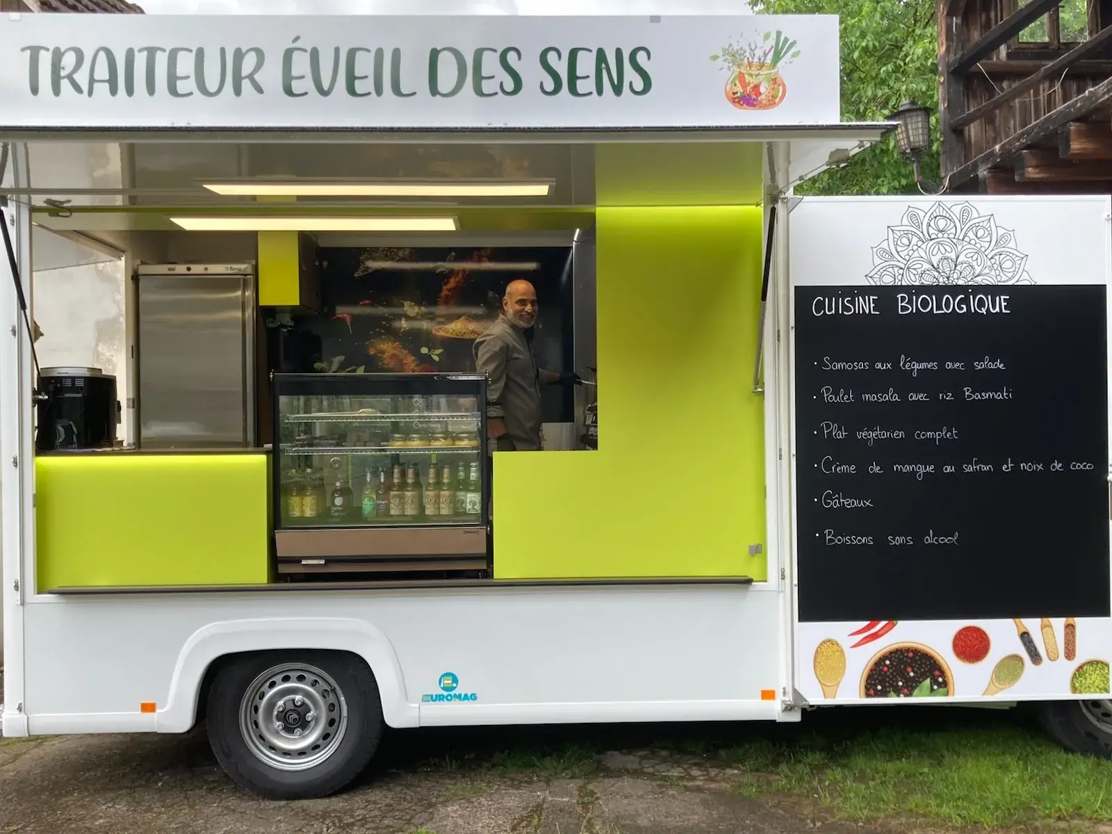 Le cuisinier souriant au comptoir du food truck, devant la vitrine de boissons