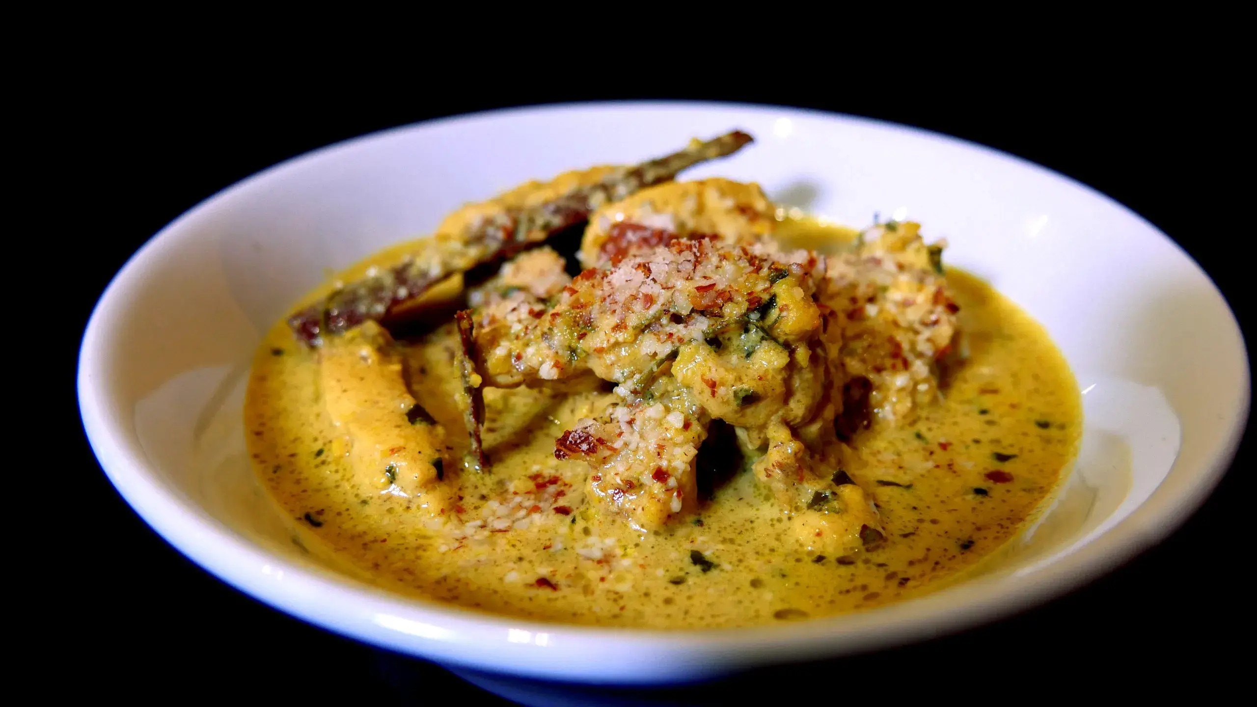 Poulet badami : curry crémeux aux amandes servi dans un bol, sur fond noir